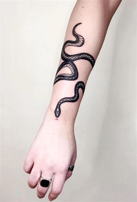 “The dagger relates to a strong, dark side, where the rose is love, joy, and beauty,” she says. . Snake wrapped around arm tattoo